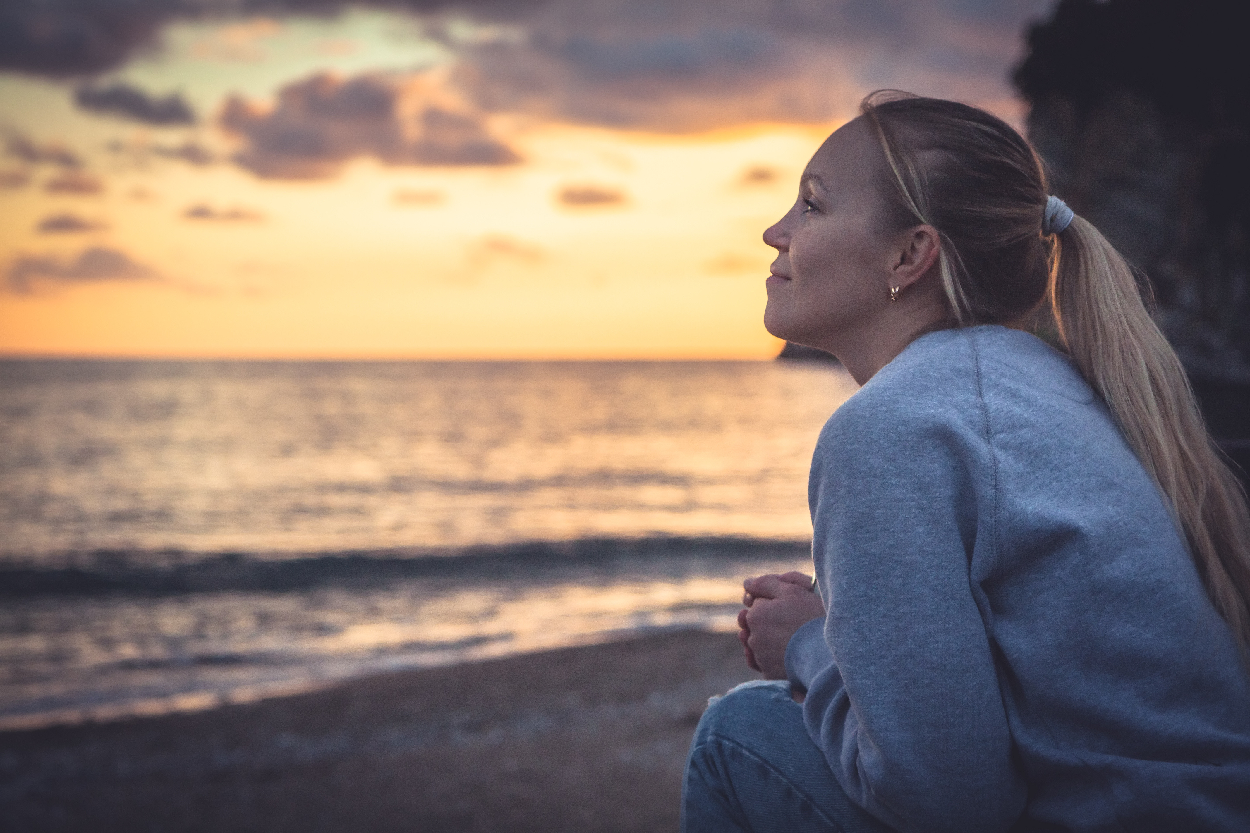 Hopeful woman looking out over the ocean at sunset.